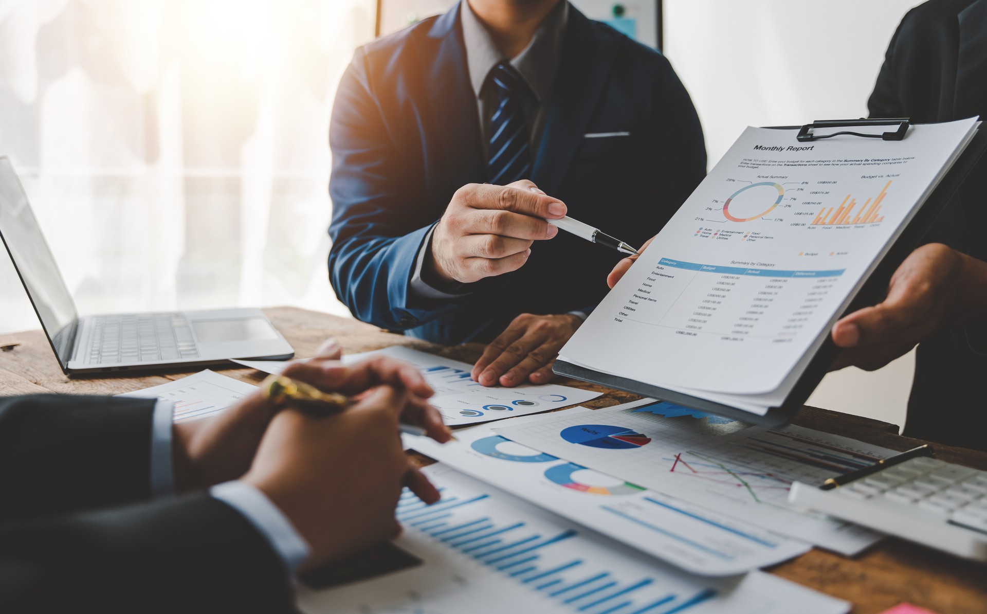 Young colleagues discuss business and analytical price charts using calculators and laptops to calculate financial, tax, accounting, statistics and analytical research ideas.