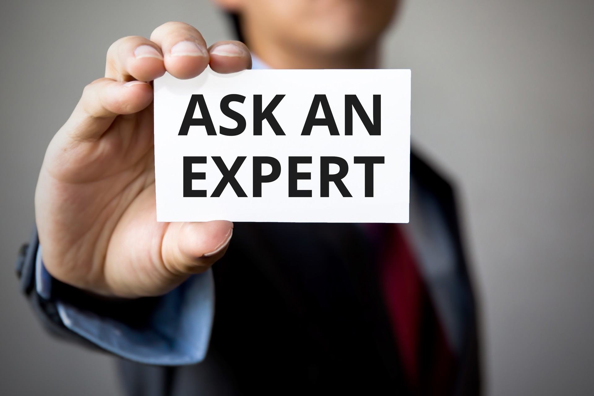 Businessman presenting 'Ask An Expert' word on white card